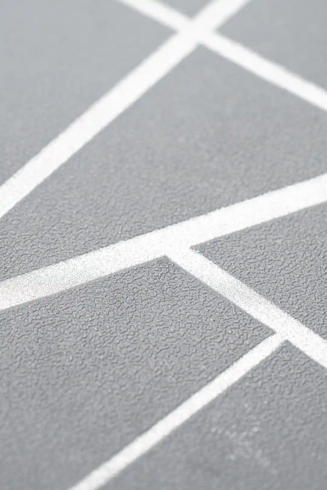 Extreme close-up of gray wallpaper texture with embossed metallic silver angular line pattern