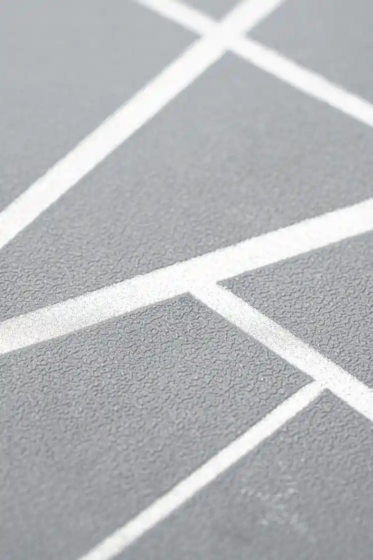 Extreme close-up of gray wallpaper texture with embossed metallic silver angular line pattern
