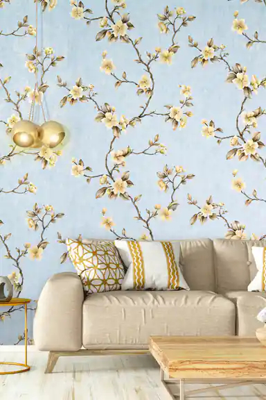 Living room scene with blue cherry blossom wallpaper behind a beige sofa with gold cushions and pendant light