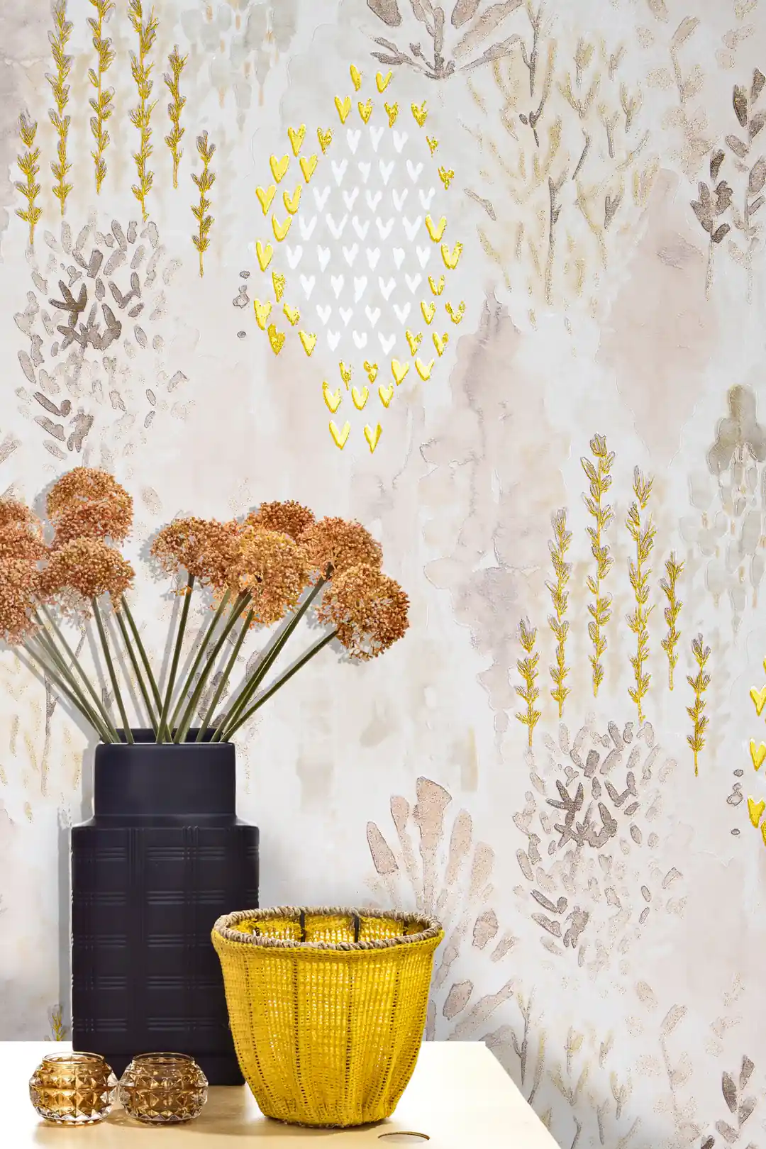 Installed sea coral wallpaper with gold and silver details behind a dark vase with dried flowers and basket