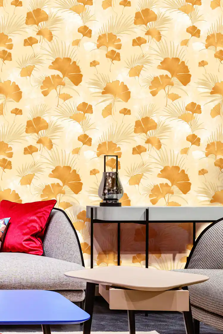 Living room with gold ginkgo wallpaper on cream behind a grey sofa with red cushion and modern furniture