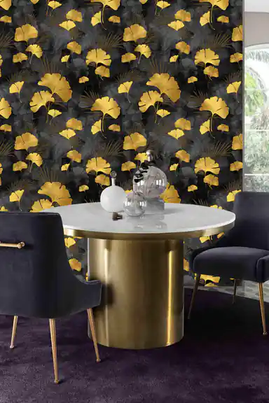 Dining room with black and gold ginkgo wallpaper behind a marble table with velvet navy chairs and gold base