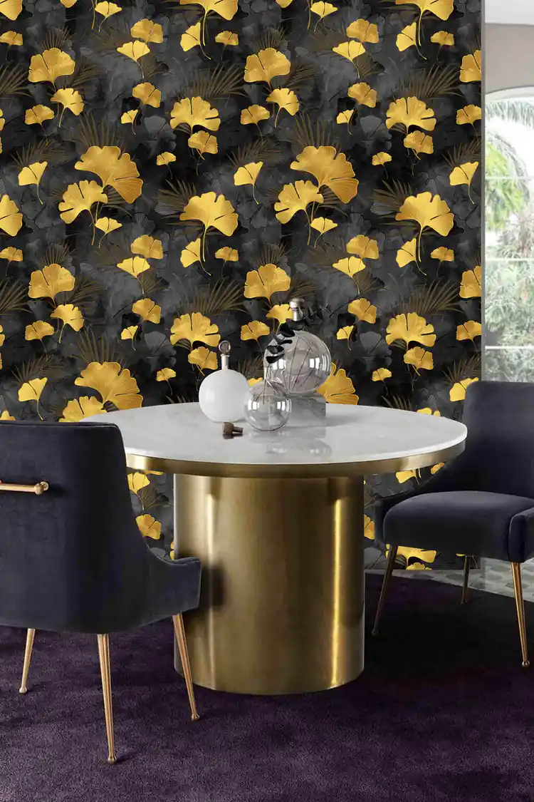 Dining room with black and gold ginkgo wallpaper behind a marble table with velvet navy chairs and gold base