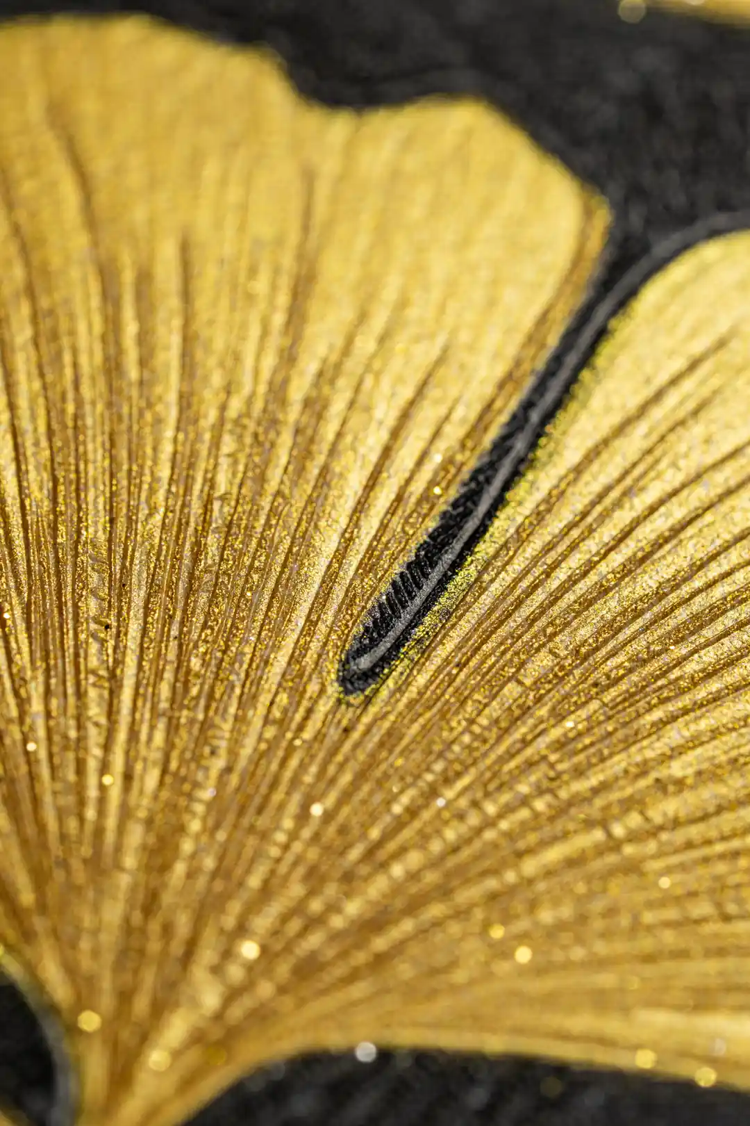 Close-up of golden ginkgo leaf texture with glitter veins on dark black wallpaper