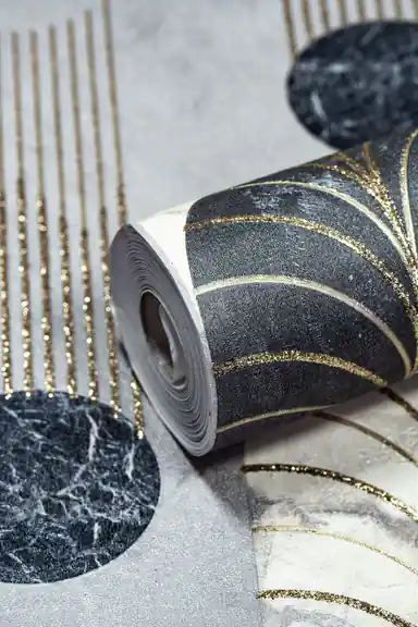 Close-up of wallpaper roll showing black marble arches with gold glitter dripping lines on grey background