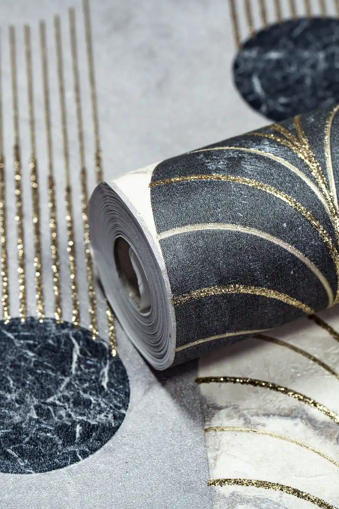 Close-up of wallpaper roll showing black marble arches with gold glitter dripping lines on grey background