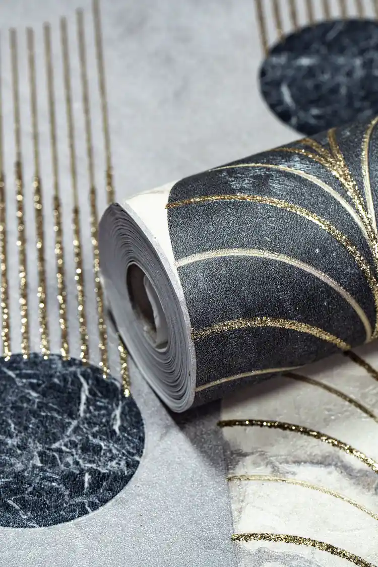 Close-up of wallpaper roll showing black marble arches with gold glitter dripping lines on grey background