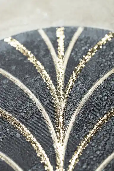 Extreme macro of gold glitter veins on a black embossed arch showing textured surface detail
