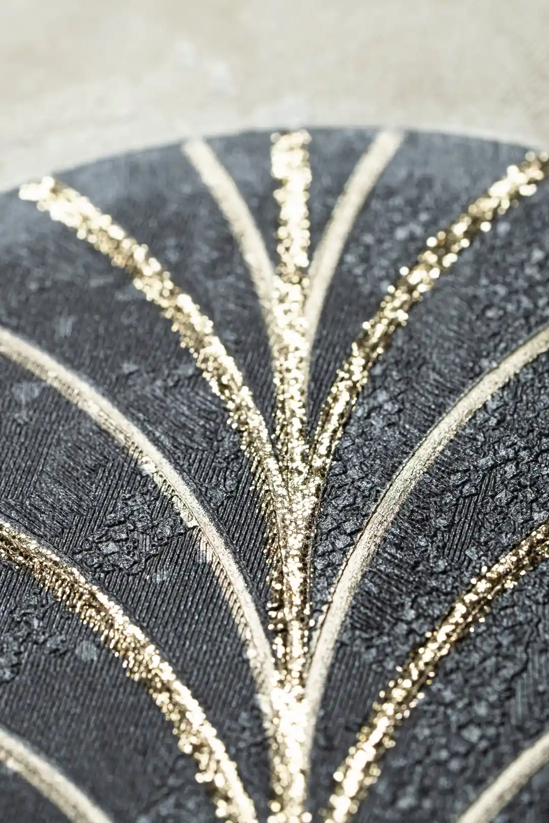 Extreme macro of gold glitter veins on a black embossed arch showing textured surface detail