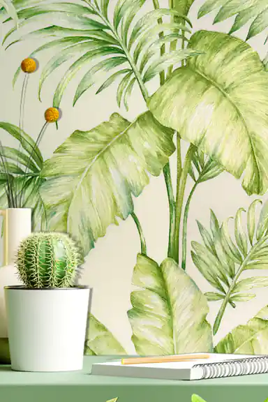 Installed tropical wallpaper close-up behind a green desk with cactus plant and notebook