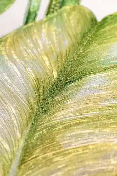 Extreme macro of green leaf texture showing gold sparkle particles and embossed vein ridges