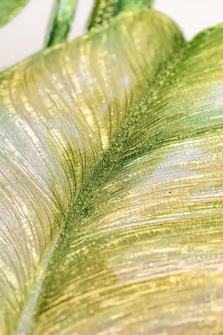 Extreme macro of green leaf texture showing gold sparkle particles and embossed vein ridges