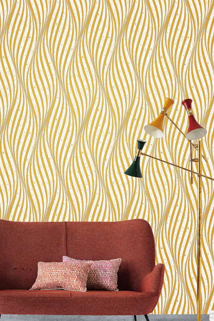 Retro living room with gold wave wallpaper behind a rust-colored sofa with patterned pillows and floor lamp