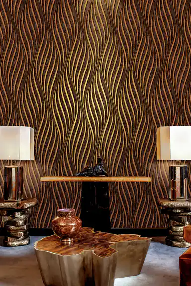 Luxury lounge with black and gold wave wallpaper behind a console table with matching lamps and gold coffee table