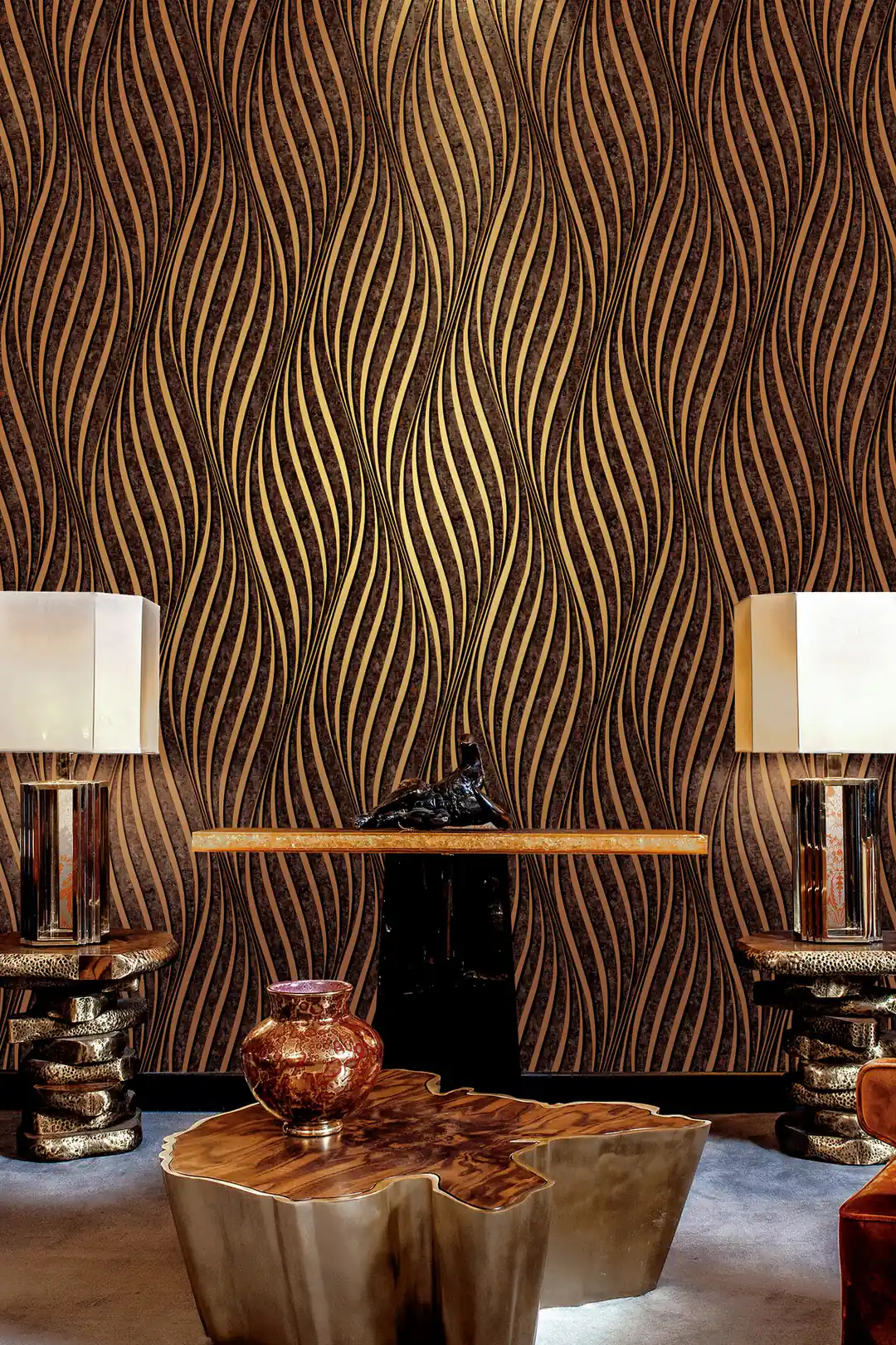 Luxury lounge with black and gold wave wallpaper behind a console table with matching lamps and gold coffee table