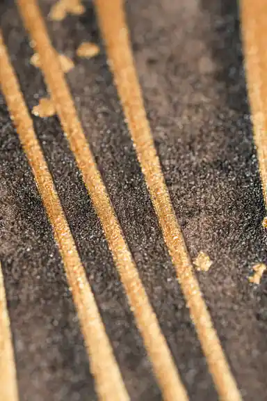 Extreme macro of gold raised lines on black textured wallpaper showing sparkle and grain detail