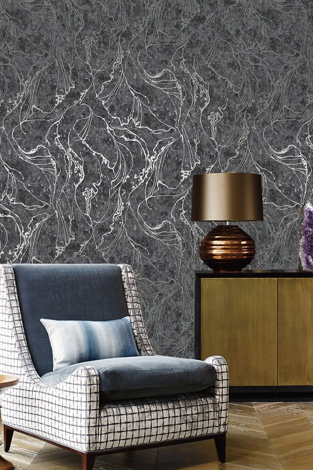 Living room with dark grey abstract wallpaper behind a plaid wing chair, brass lamp, and wooden sideboard