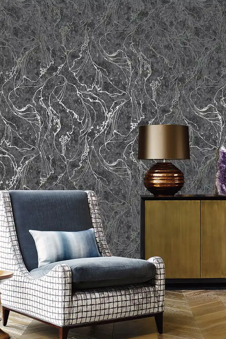 Living room with dark grey abstract wallpaper behind a plaid wing chair, brass lamp, and wooden sideboard