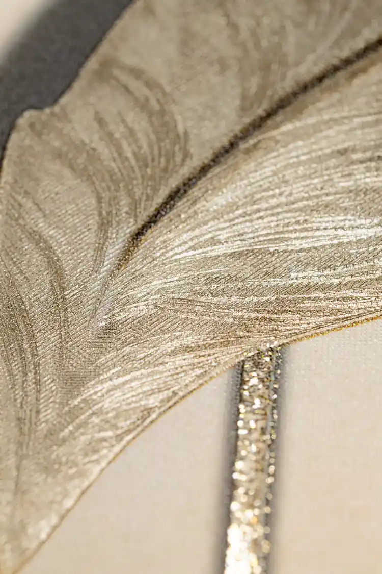 Extreme macro of an embossed leaf showing champagne-toned veins and fine textured detail on cream wallpaper