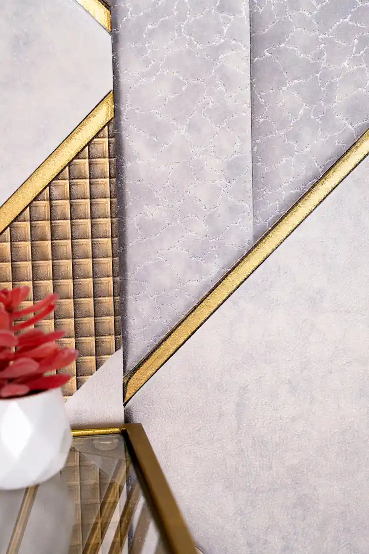 Detailed view of metallic gold quilted grid panels and textured grey marble surfaces on geometric wallpaper with red flowers in foreground