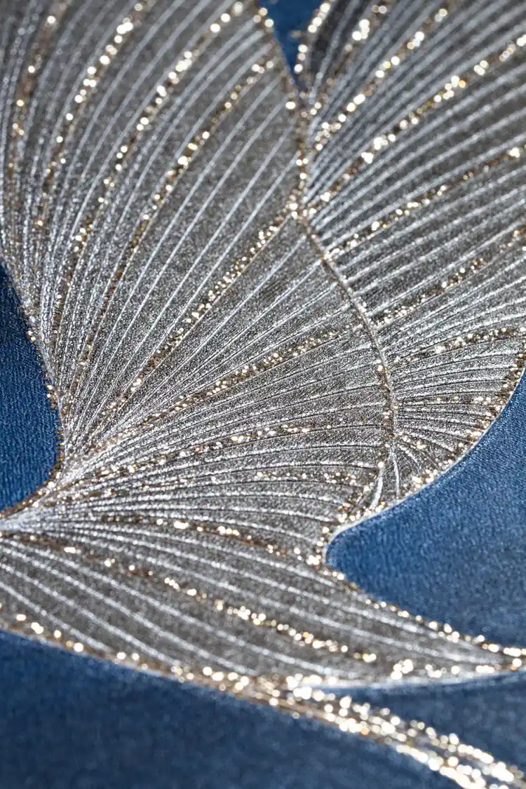 Extreme macro of silver and gold glitter crane wing feathers showing fine ridged texture on navy wallpaper