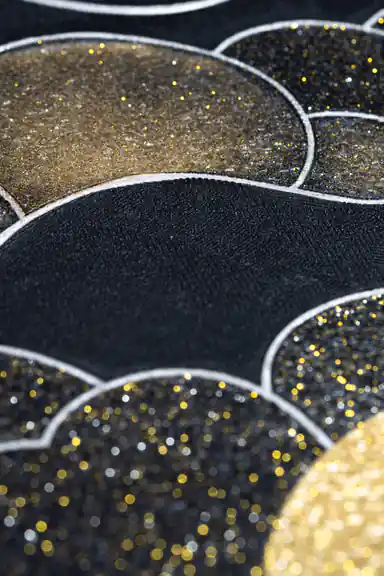 Extreme macro of black and gold glitter scallop cloud texture showing sparkle detail up close