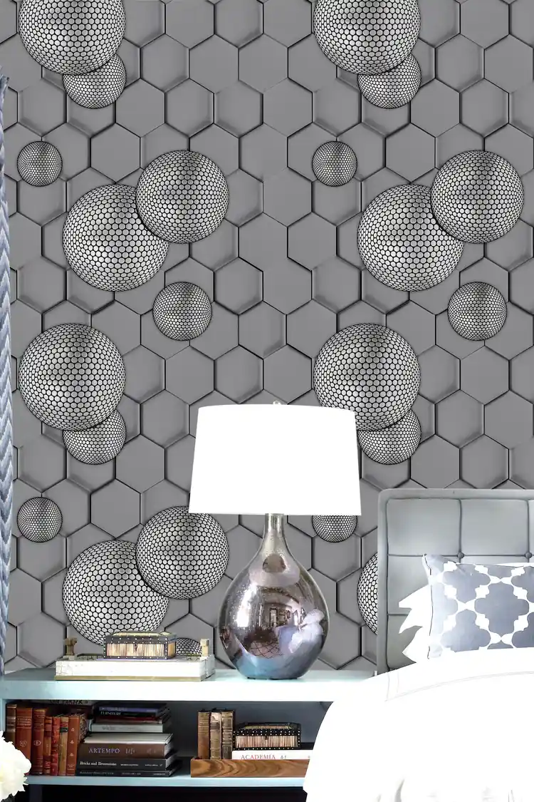 Grey geometric hexagon wallpaper installed in a room with textured 3D spheres beside a white lamp and silver vase