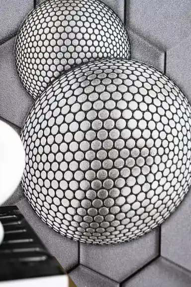 Close-up of two overlapping 3D textured spheres with circular dot pattern on grey hexagon wallpaper background