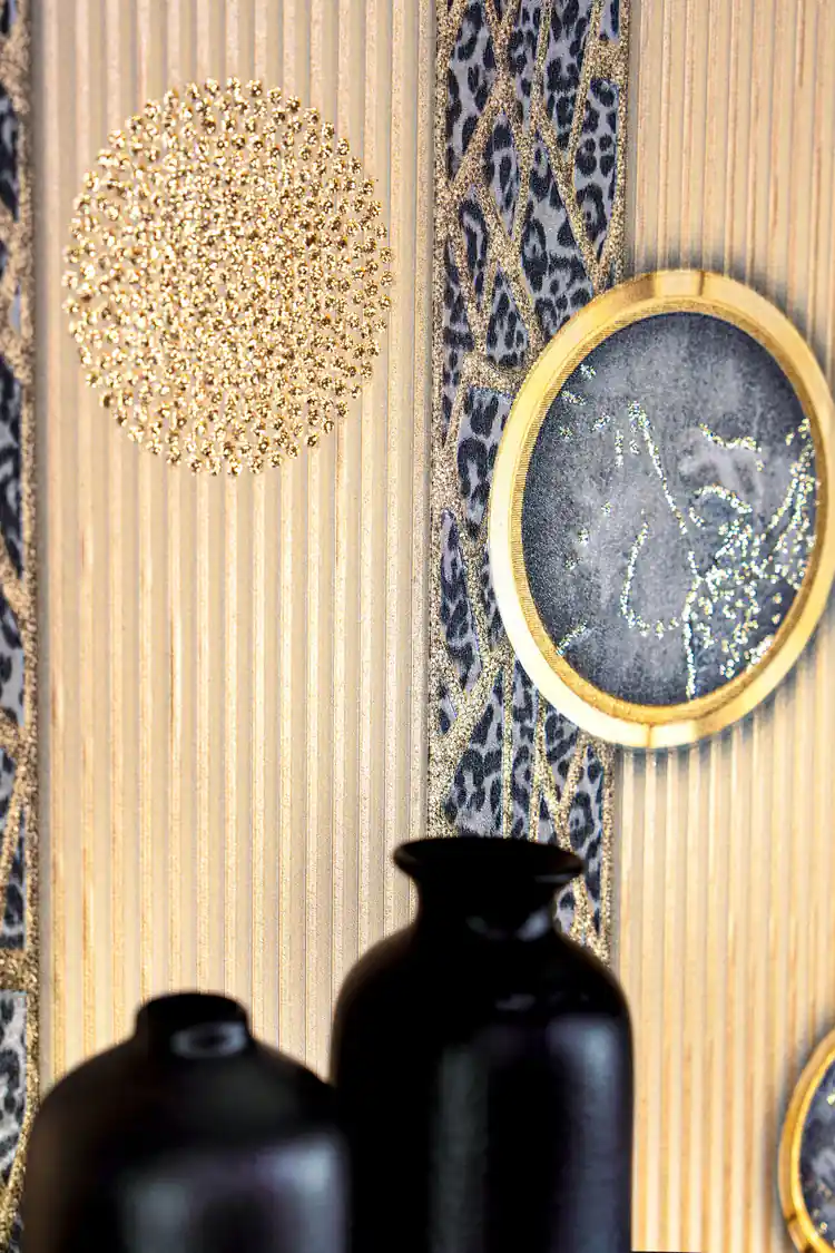Detail shot of gold-rimmed marble medallion and glitter circle on cream striped wallpaper with dark vases