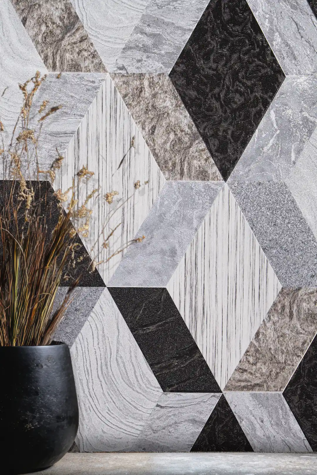 Installed view of geometric marble tile wallpaper with grey and black diamond shapes beside a dark vase