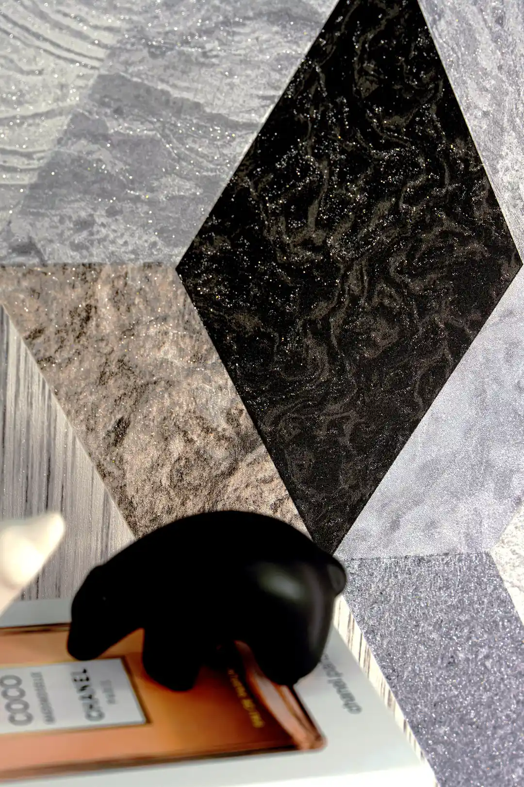Close-up of diamond-shaped marble tile wallpaper showing black and grey textures with silver glitter accents