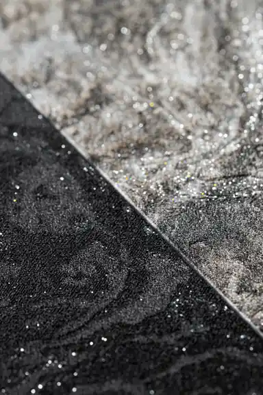 Extreme close-up macro of silver shimmer and glitter particles on black and grey marble tile surface