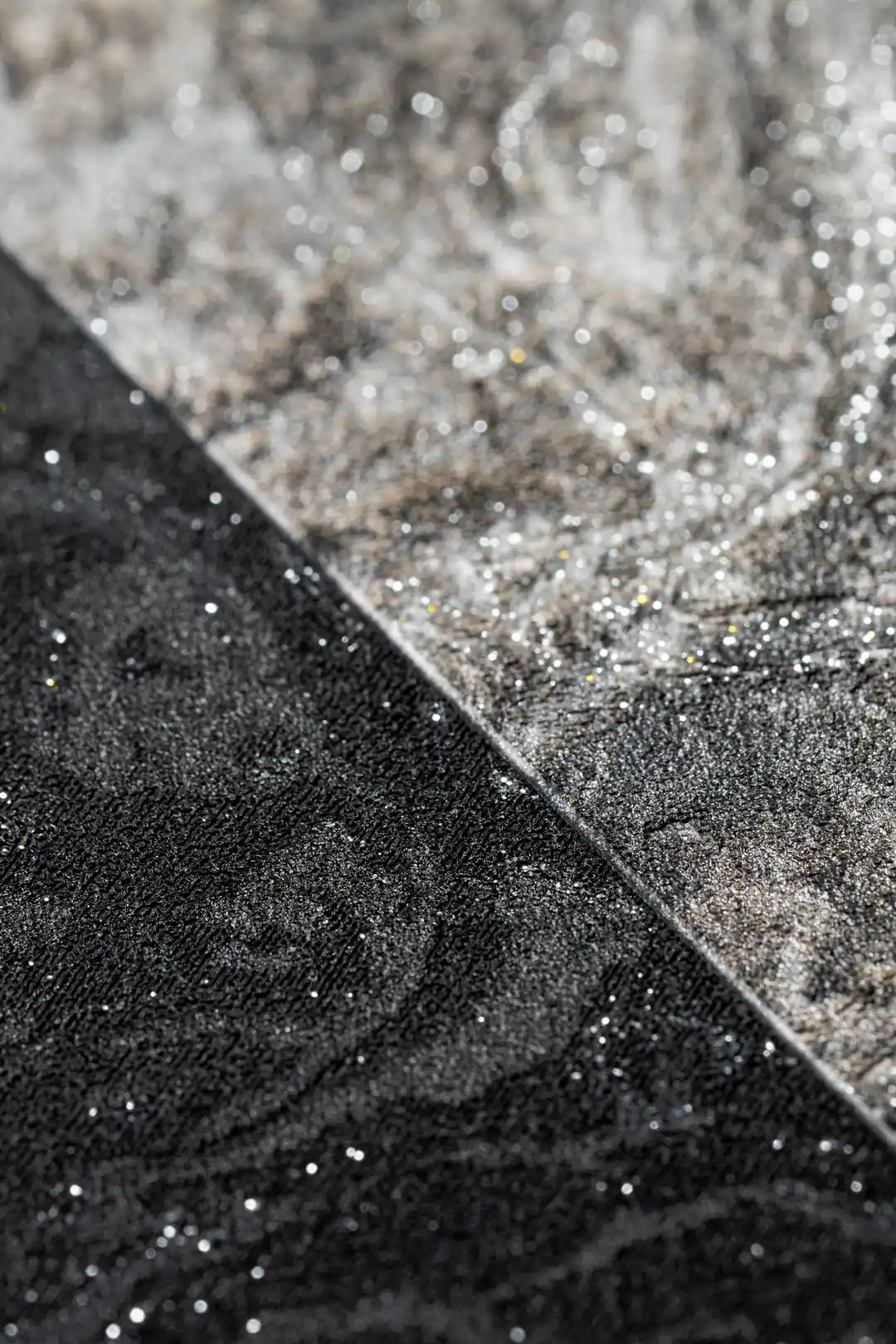 Extreme close-up macro of silver shimmer and glitter particles on black and grey marble tile surface