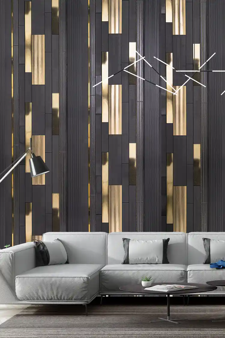 Dark charcoal and gold vertical strip wallpaper installed in a modern living room with grey sectional sofa and geometric light fixture