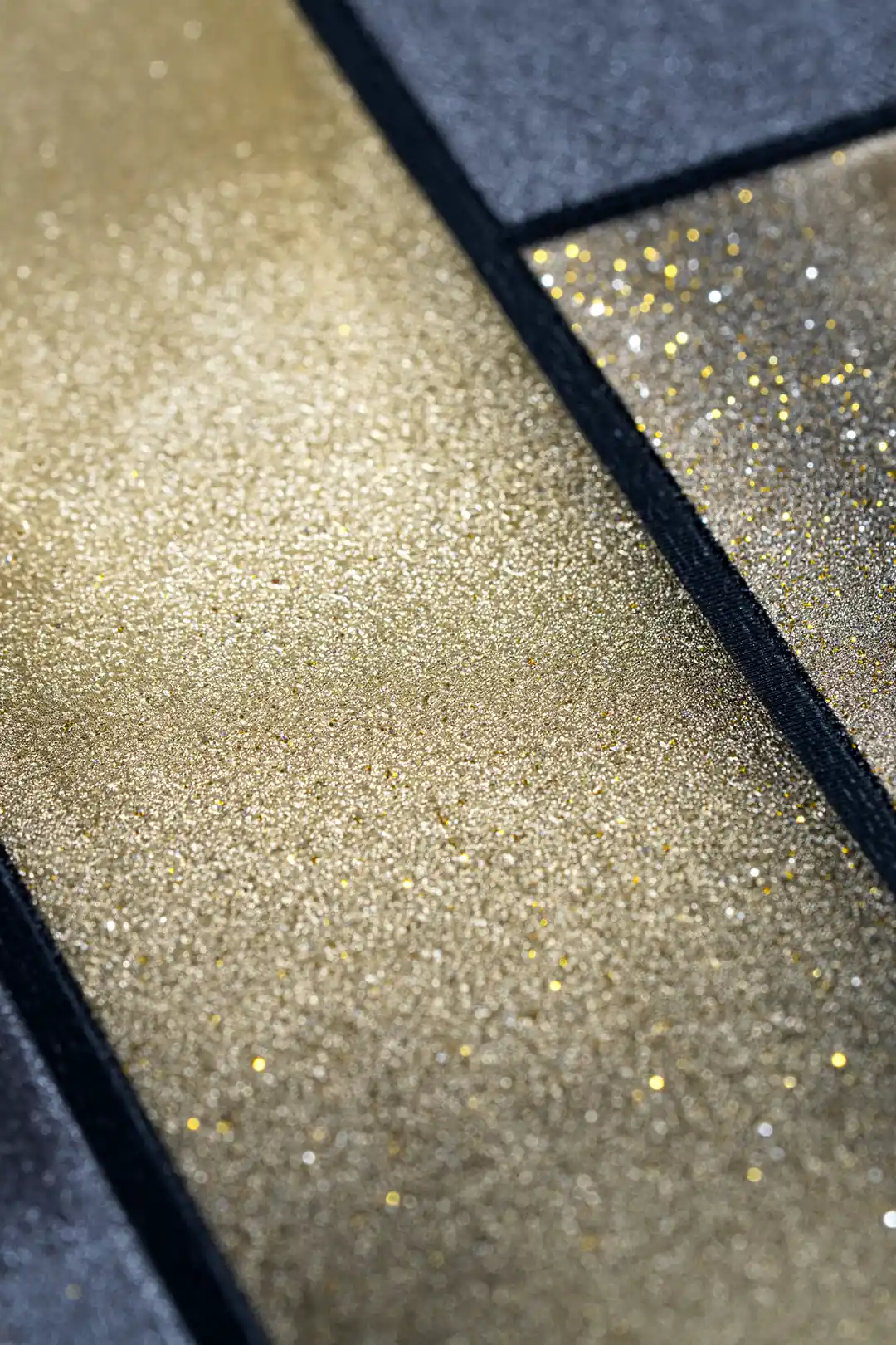 Extreme close-up macro of gold glitter panel surface meeting dark charcoal textured wallpaper edge