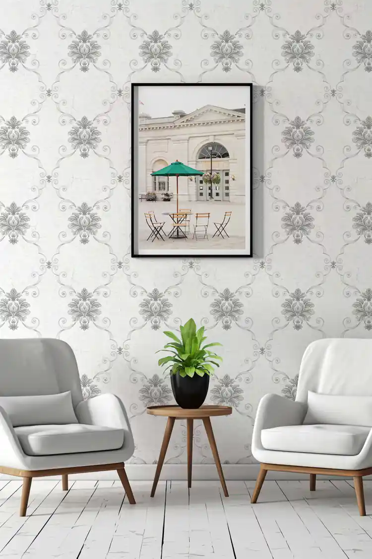 Silver damask wallpaper in an elegant sitting room with grey armchairs, potted plant, and framed wall art