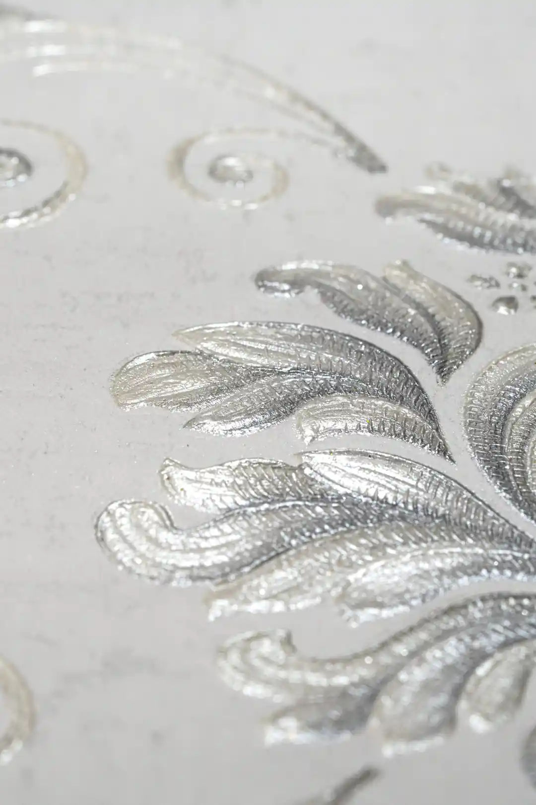 Extreme close-up macro of embossed silver leaf detail showing metallic sheen and raised texture