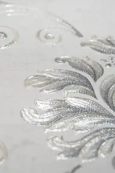 Extreme close-up macro of embossed silver leaf detail showing metallic sheen and raised texture
