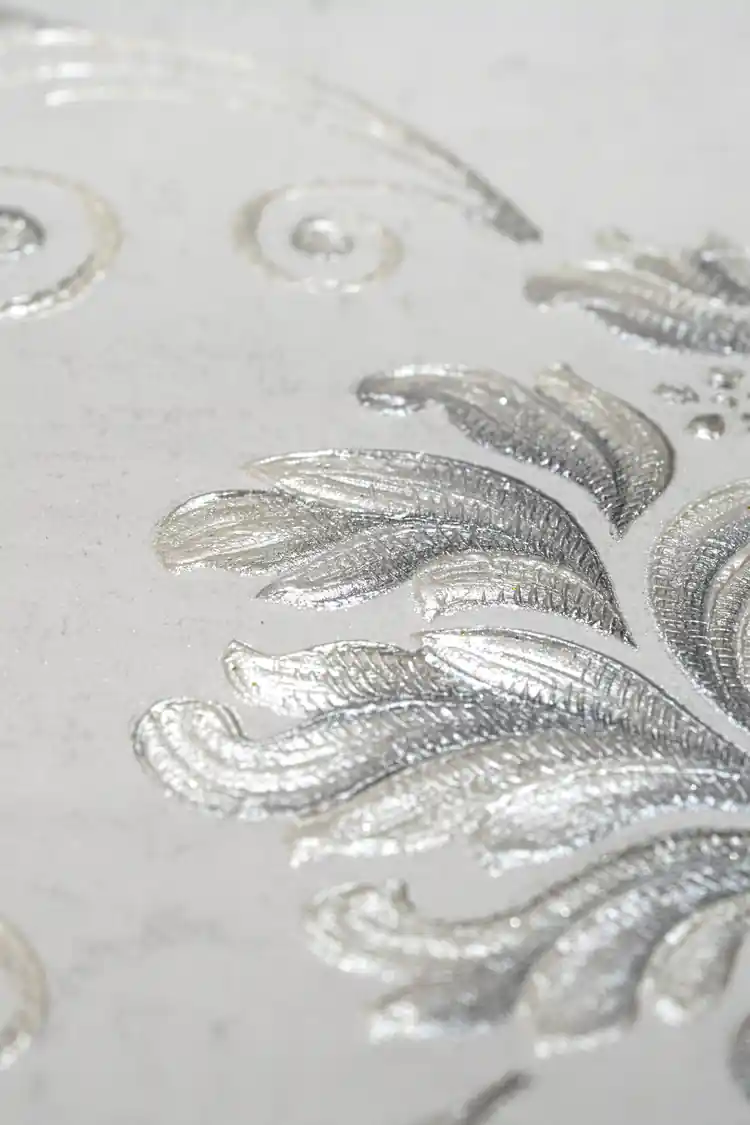Extreme close-up macro of embossed silver leaf detail showing metallic sheen and raised texture