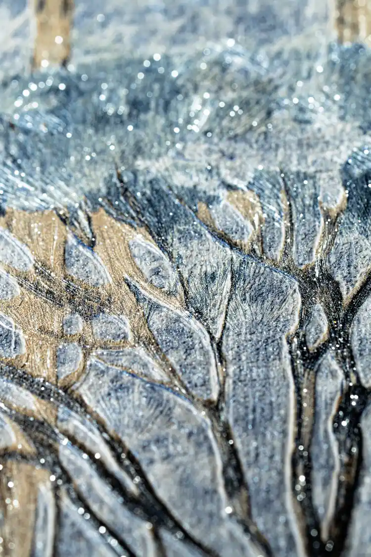 Extreme close-up macro of textured tree foliage with gold glitter particles on blue-grey wallpaper