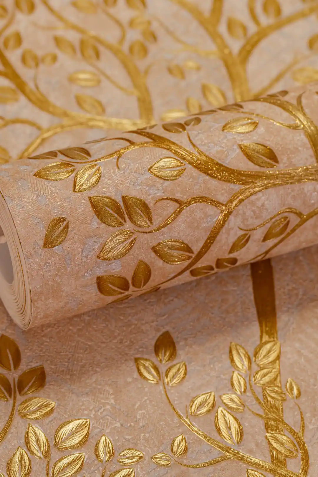 Rolled beige wallpaper with embossed golden glitter tree branches and leaf pattern on cream textured base
