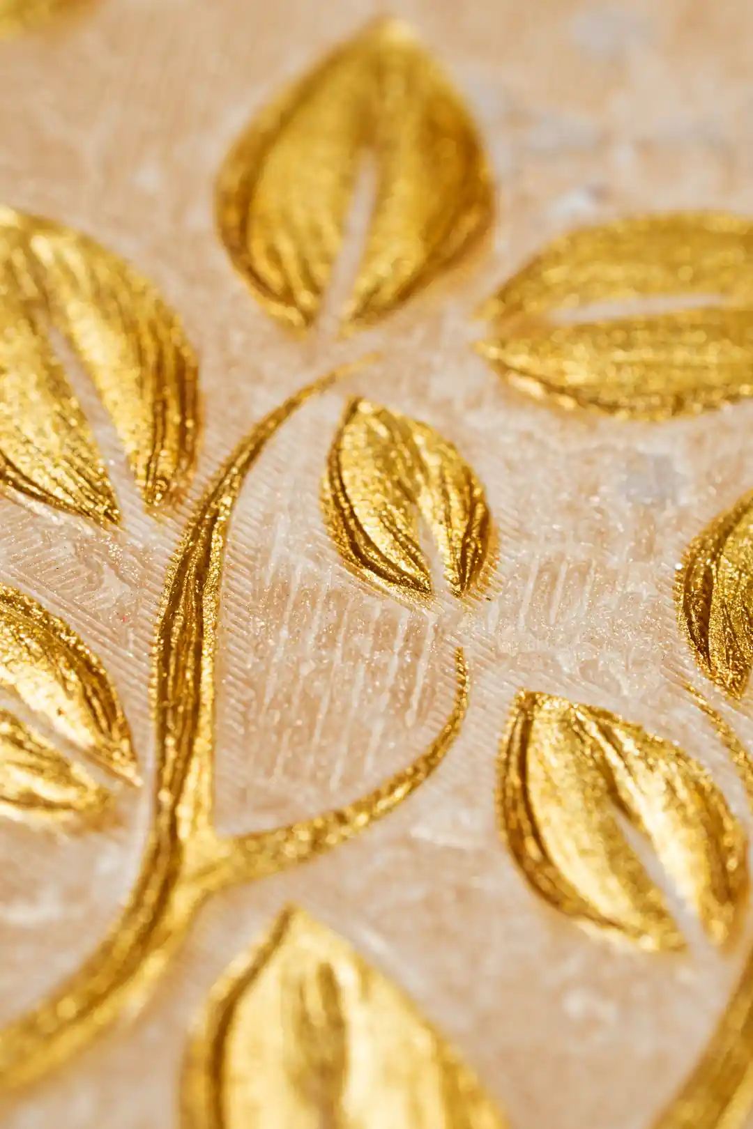 Extreme close-up macro of embossed golden glitter leaves showing raised texture and metallic sheen