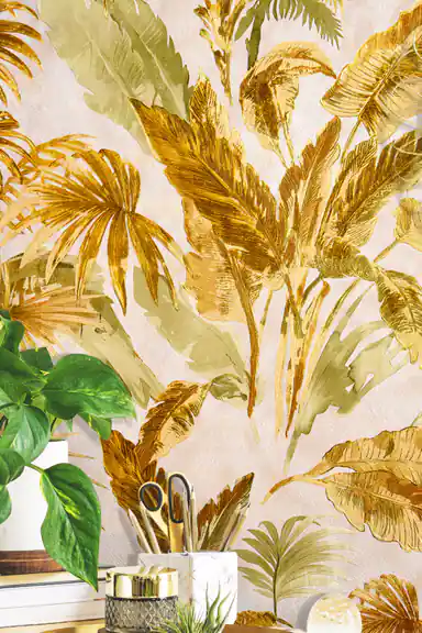 Installed wall close-up of gold and green tropical palm frond wallpaper with blurred houseplant in front