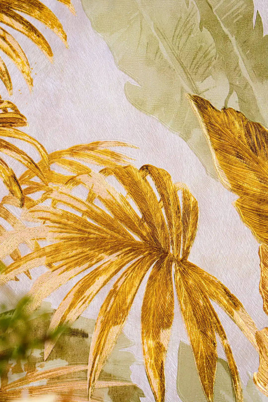 Close-up of golden tropical palm and banana leaf fronds with metallic finish on the wallpaper surface