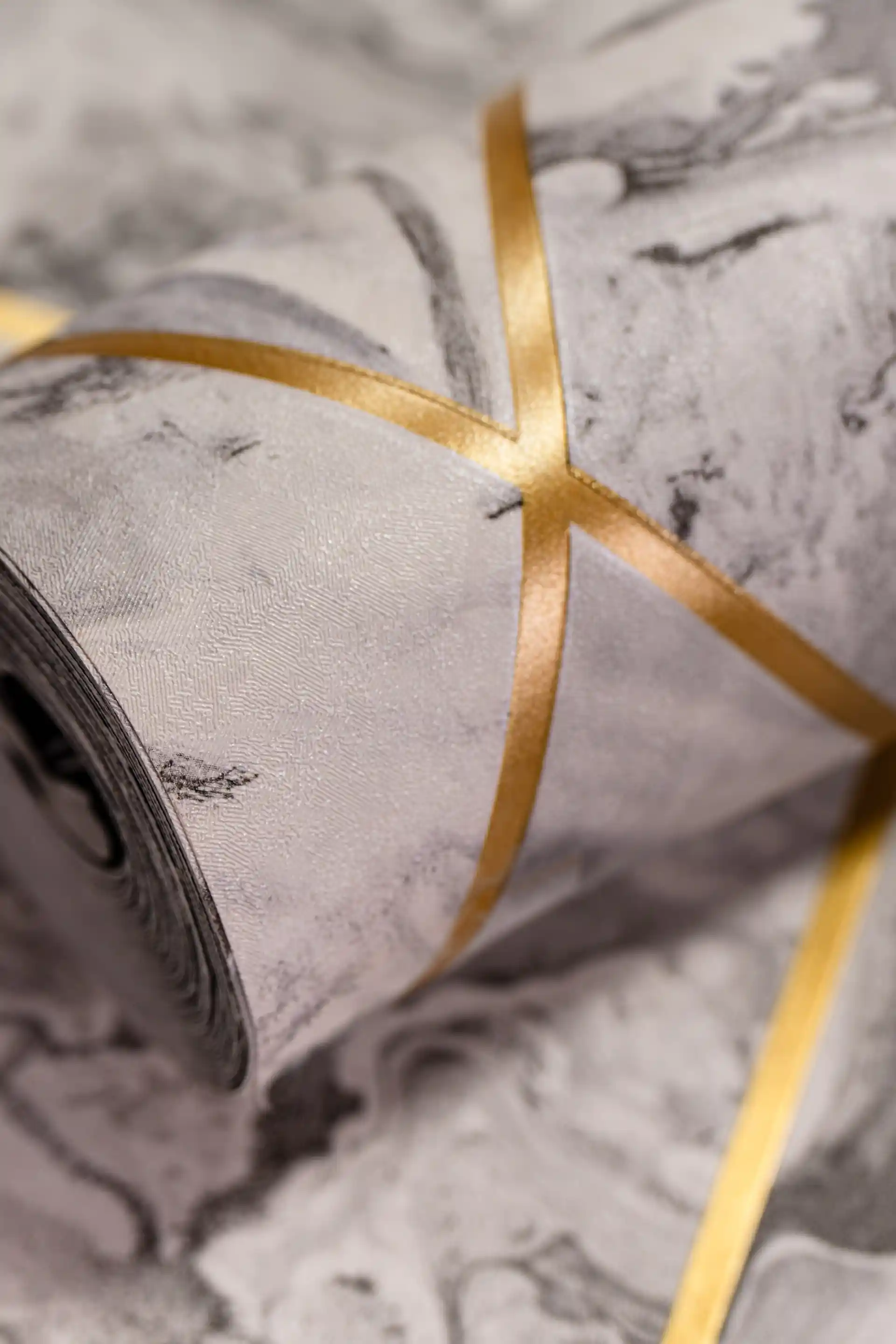 Rolled grey marble wallpaper with gold geometric crisscross lines creating diamond panel pattern
