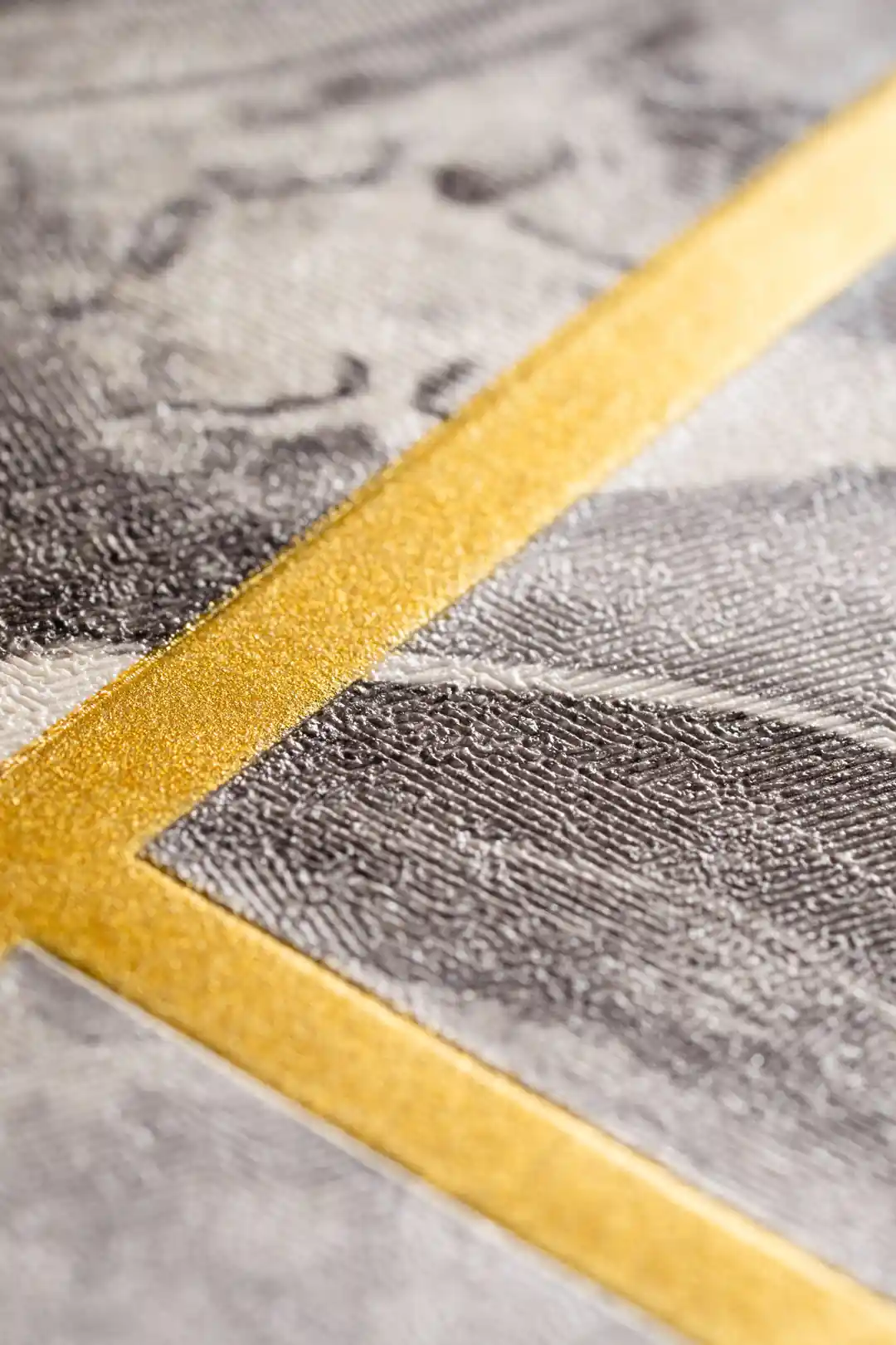 Extreme close-up macro of gold metallic geometric line on grey marble textured wallpaper surface