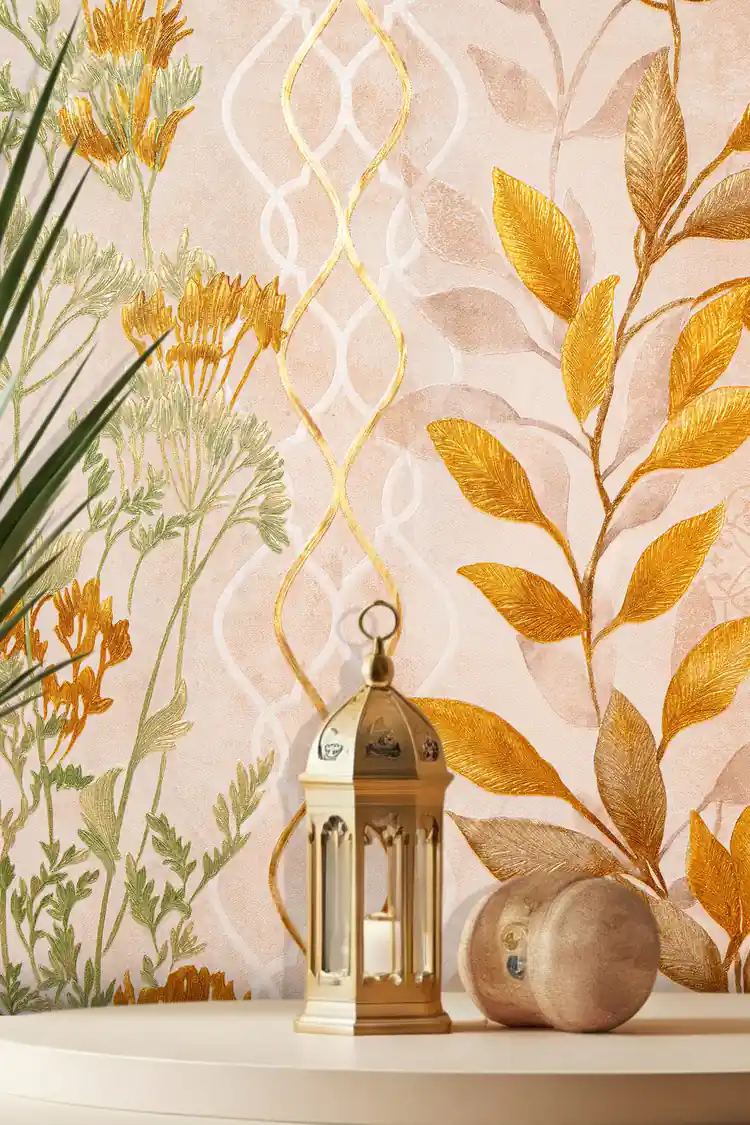 Close-up of golden fern trellis wallpaper with autumn-colored leaves beside a gold Moroccan lantern and wooden sphere on table