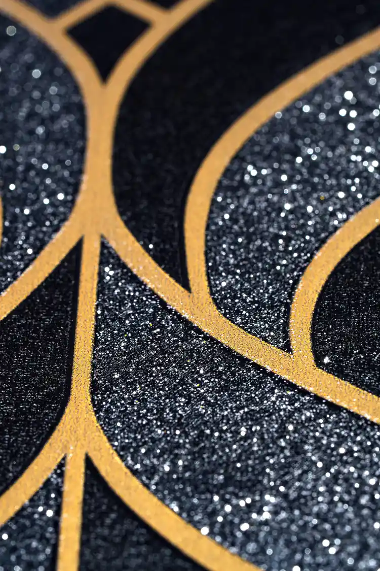 Extreme close-up of black wallpaper with gold leaf outline pattern showing glitter accent detail