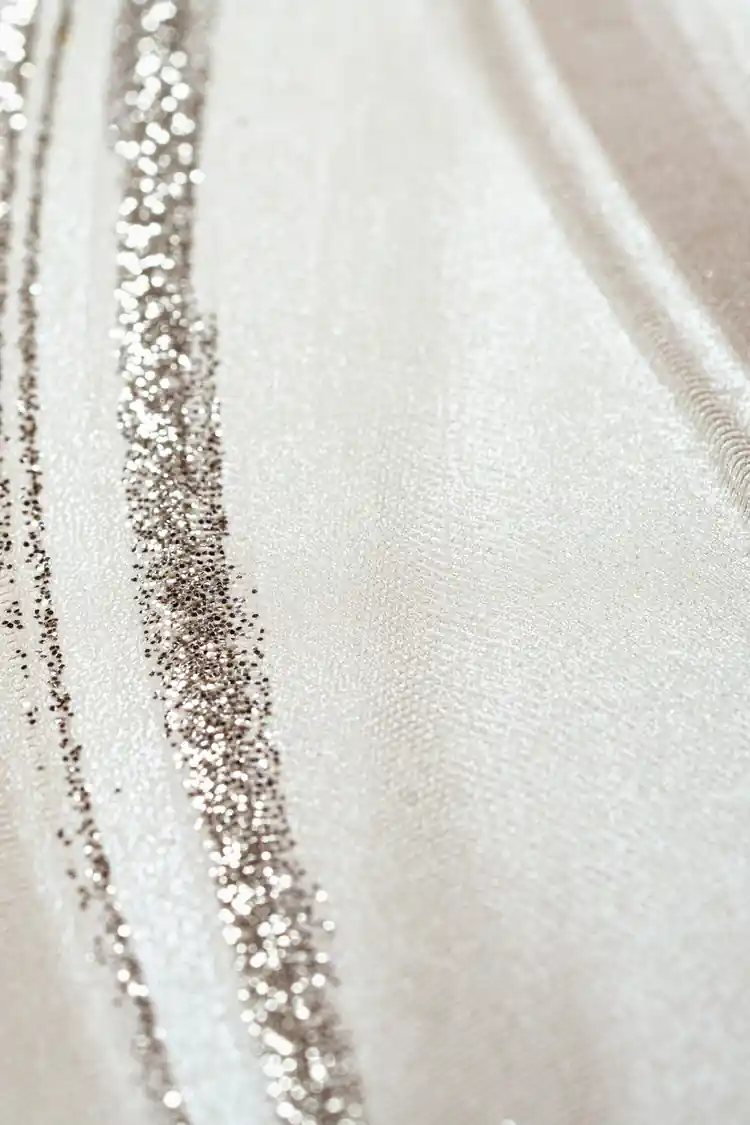 Extreme close-up macro of pearl silk wave wallpaper texture showing silver glitter particles along curved lines