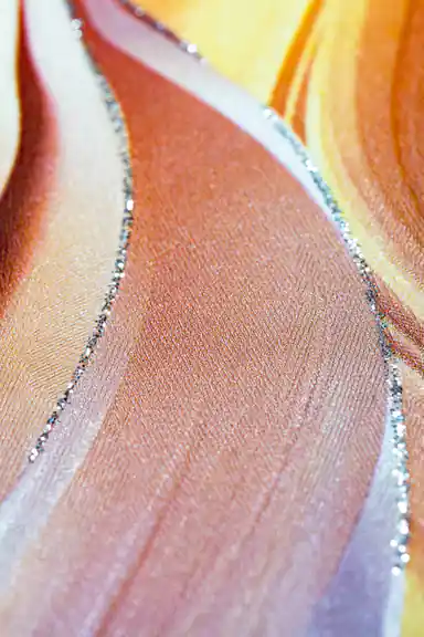 Extreme close-up macro of flowing orange and peach feather texture with silver glitter line on surface